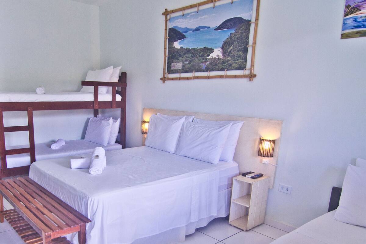 A bedroom with bunk beds, a bedside table, a nightstand, and a painting on the wall.