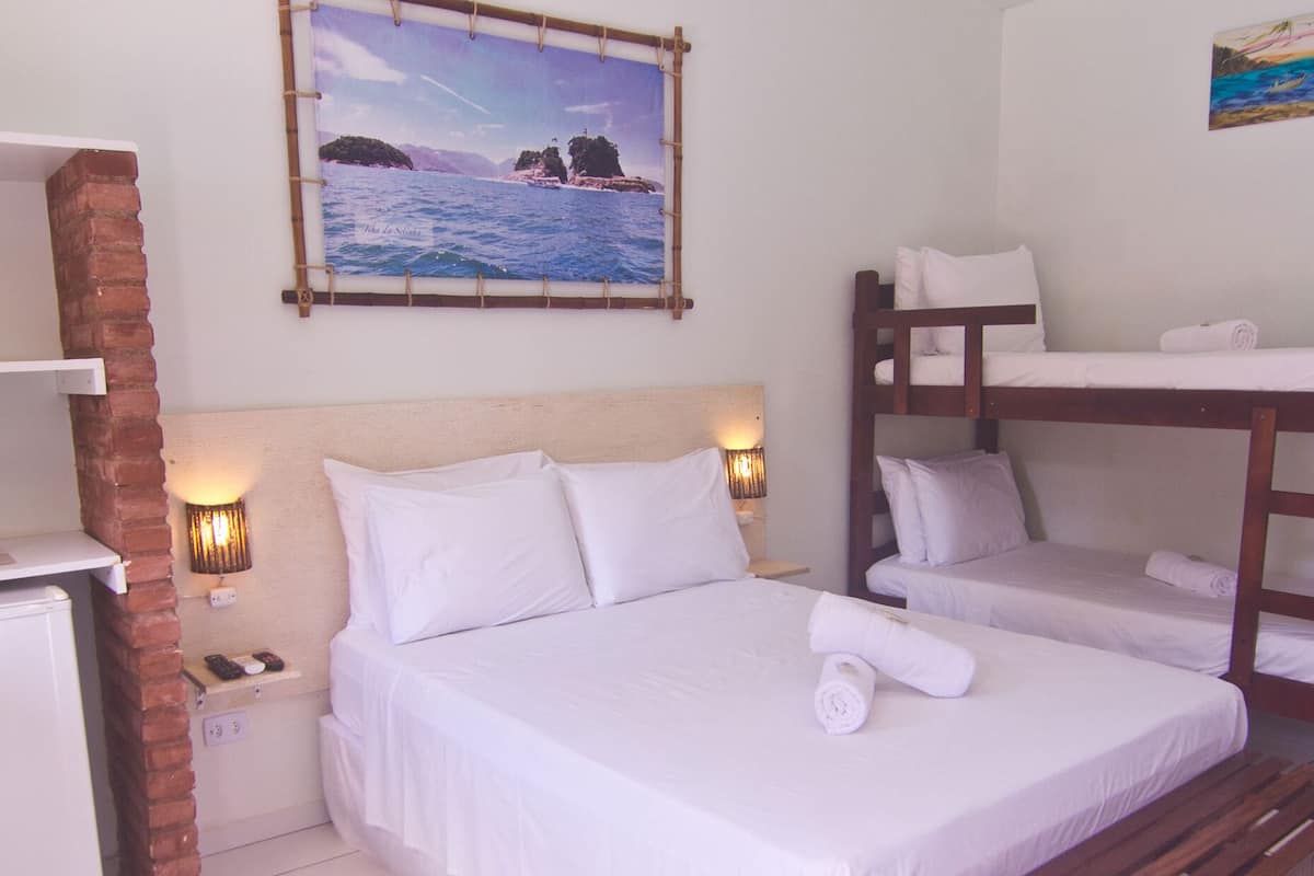 A room with a bed, a bunk bed, a desk with a computer, and a small refrigerator.