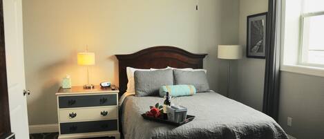 A neatly arranged bedroom with a bed, bedside tables, lamps, and a window.