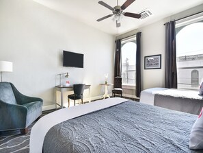 A hotel room with a bed, a desk, a chair, a television, and a window with curtains.