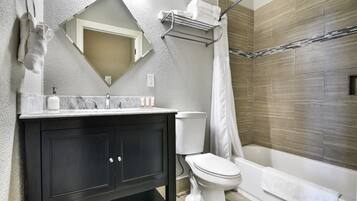 Un baño moderno con tocador negro, accesorios blancos y zona de ducha.