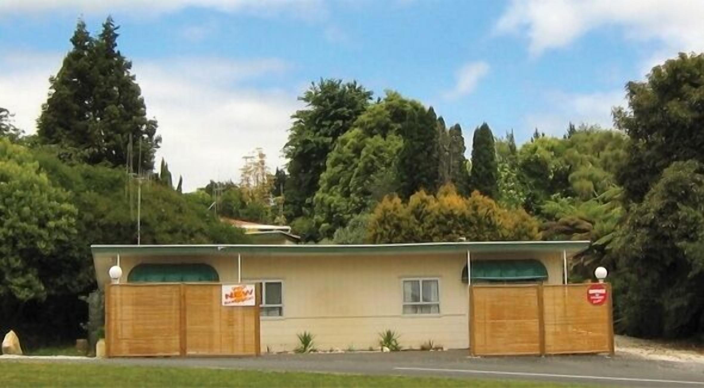 A small, single-story building with a flat roof, two windows, and a sign on the front.