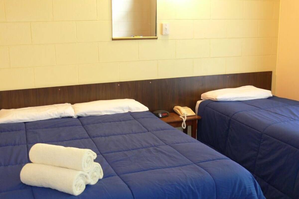 A hotel room with two beds, a bedside phone, and a mirror on the wall.