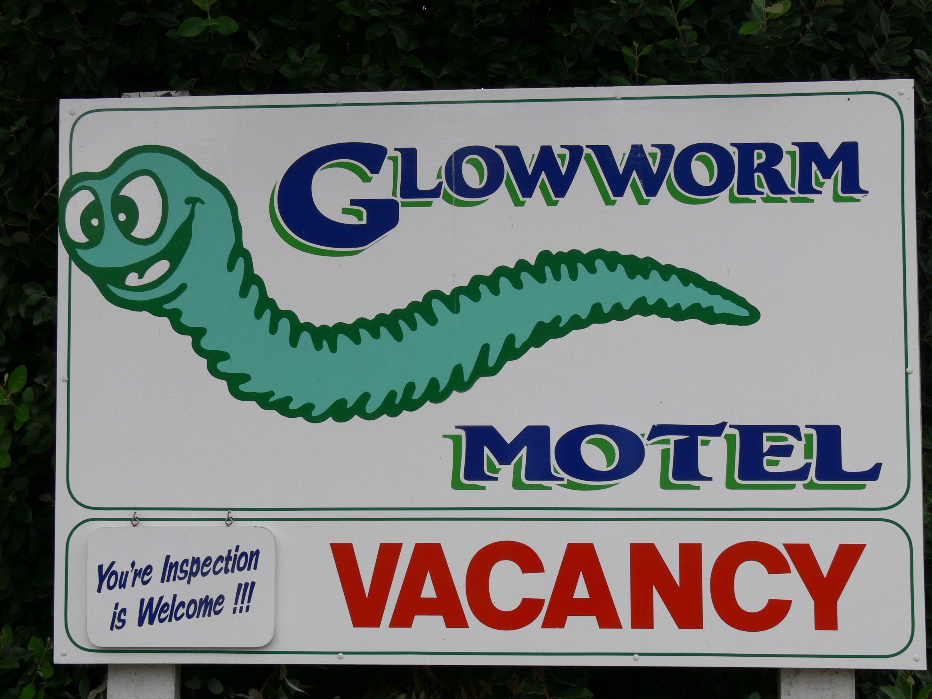 A motel sign with a green worm graphic and the words "Glowworm Motel" and "VACANCY".