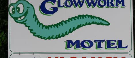 A motel sign with a green worm graphic and the words "Glowworm Motel" and "VACANCY".
