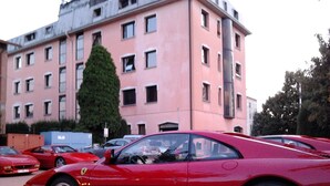 A red sports car parked in front of a pink building with multiple windows and a tree. - Hotel Alexander (Fiorano Modenese)