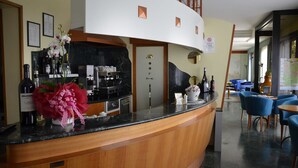 A hotel reception area with a curved wooden counter, a coffee machine, and a selection of bottled beverages. - Hotel Alexander (Fiorano Modenese)