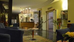 A hotel lobby with a reception desk, seating area, and a reception counter. - Hotel Alexander (Fiorano Modenese)