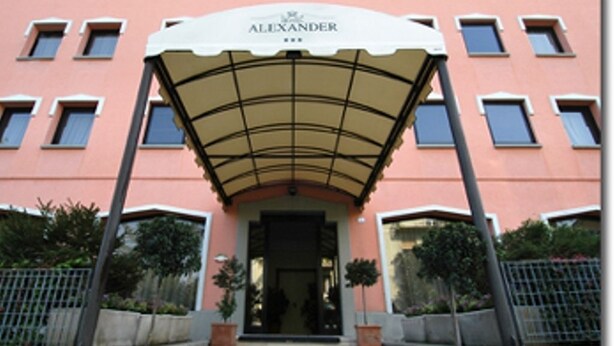 A building with a pink facade and a covered entrance labeled "ALEXANDER." - Hotel Alexander (Fiorano Modenese)