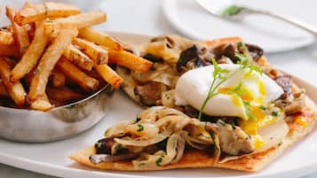 En tallrik med ett pocherat ägg, svamp och en portion pommes frites.