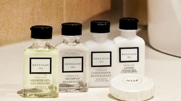Cuatro productos Beekman 1801: gel de ducha, champú, acondicionador y loción, junto con una pastilla de jabón.