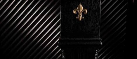 Une porte en bois noir ornée d’un écusson doré en forme de fleur de lys.