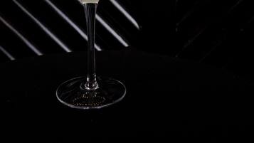 Un cóctel en una copa de martini con una decoración de cáscara de limón, sobre un fondo oscuro con líneas diagonales y un adorno de serpiente.