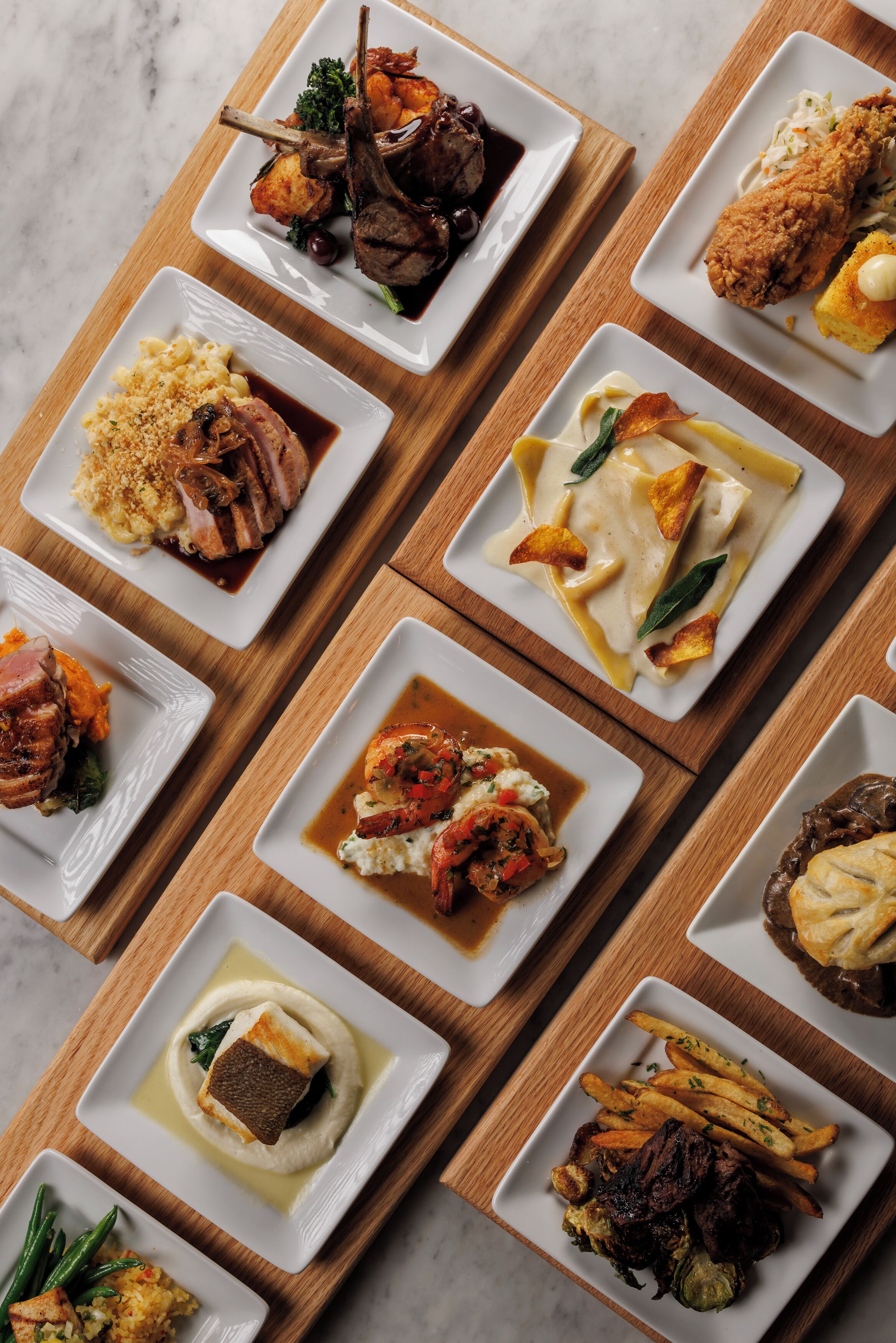 A variety of dishes arranged on rectangular white plates, each with different food items and garnishes.