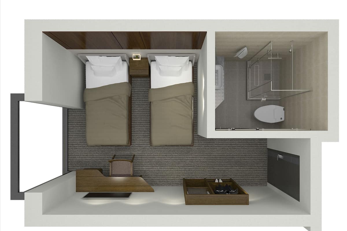 Una habitación de hotel compacta con dos camas, un escritorio pequeño, zona de ducha y un inodoro.