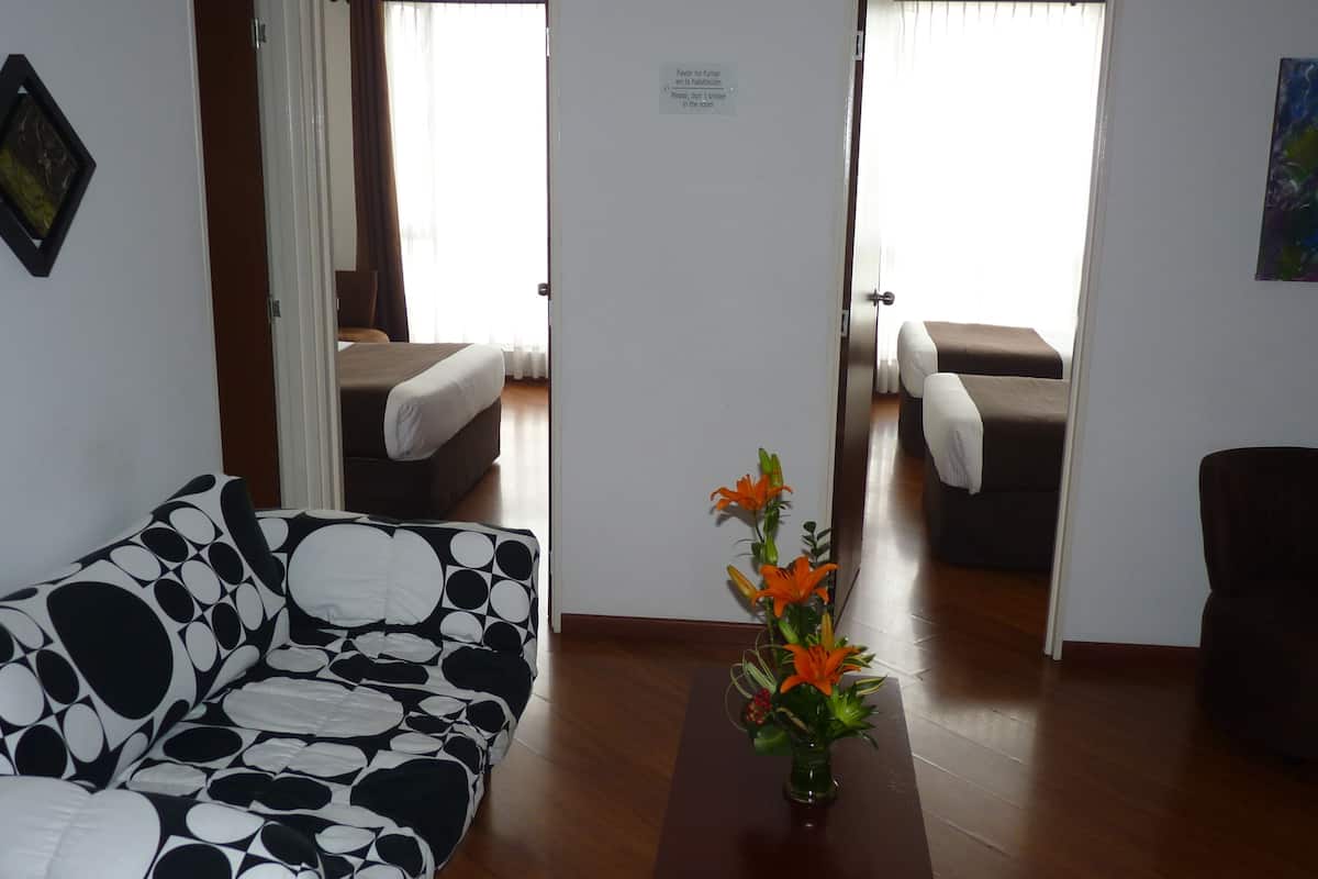 Une chambre d’hôtel avec un canapé, une petite table ornée de fleurs, un lit et une chaise.