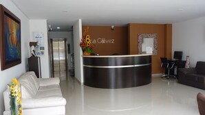 A modern reception area with a curved desk, a sofa, and a coffee table with a vase of sunflowers.