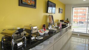 A buffet setup with various food containers and a coffee machine.