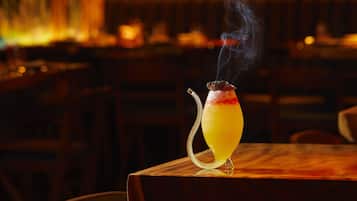 A cocktail on a wooden table in a dimly lit bar with a warm ambiance.