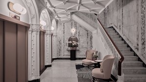 Eine prachtvolle Halle mit Marmorwänden, einer Treppe und stilvollen Sitzgelegenheiten.