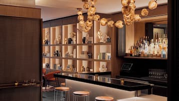 A bar area with a long counter, stools, and a variety of bottles and glasses.