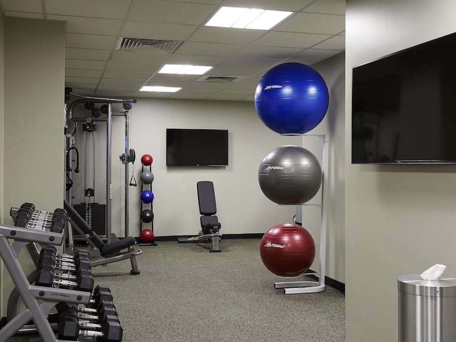 Ein Fitnessraum mit Trainingsgeräten, einem Fernseher und Übungsbällen.