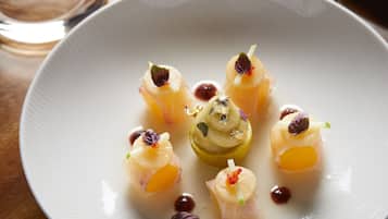A white plate with a central dessert and surrounding garnishes.