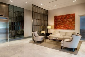 A modern lobby with a sofa, two armchairs, a coffee table, and a decorative wall.
