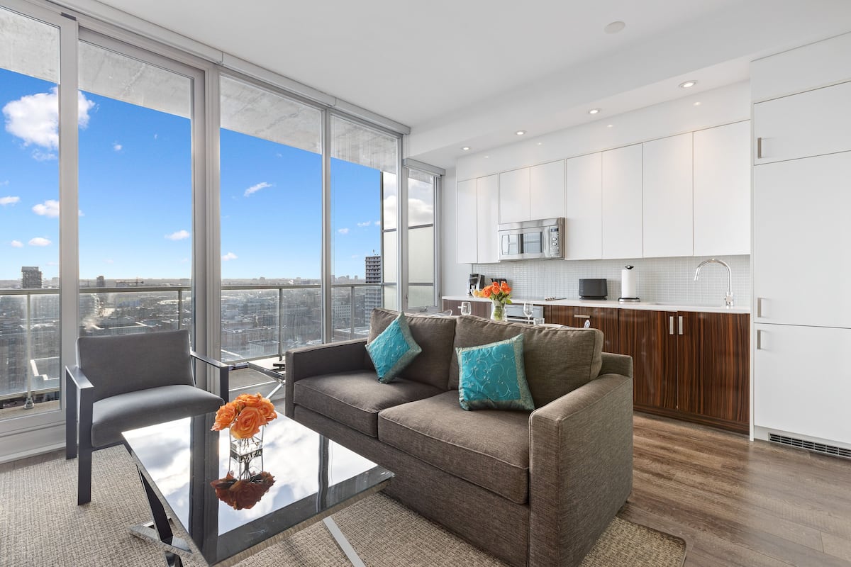 A modern living room with a sofa, coffee table, and a view of the city through large windows.