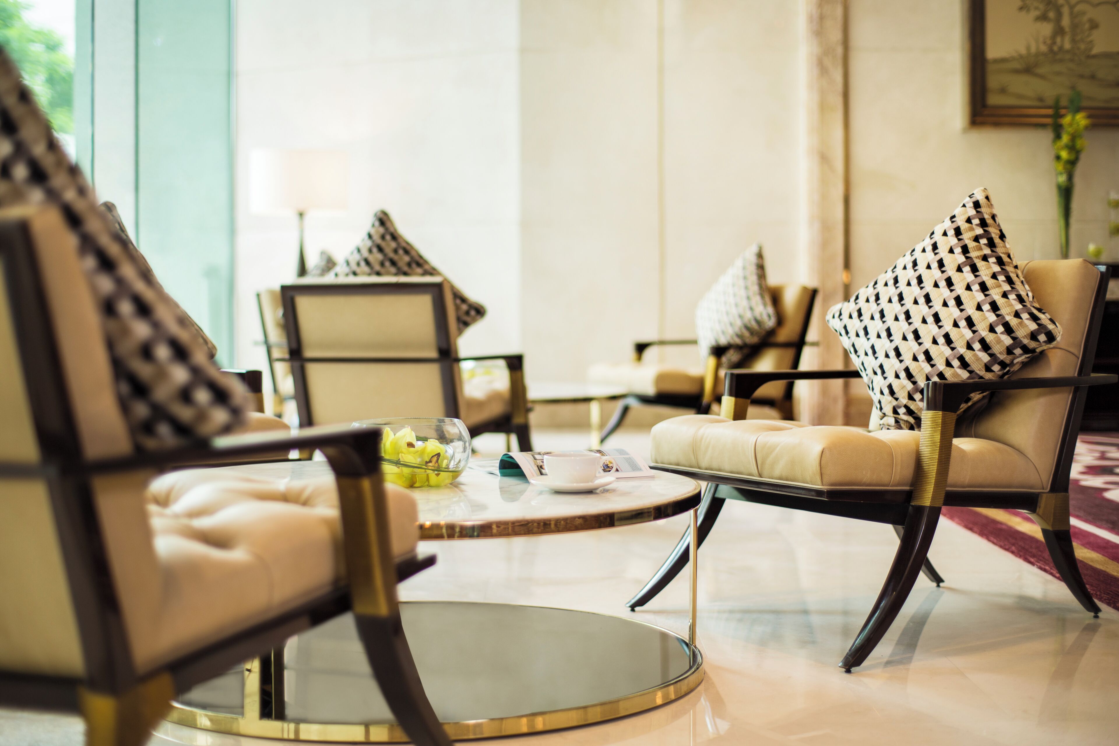 A modern lounge area with leather armchairs, a glass coffee table, and patterned throw pillows.