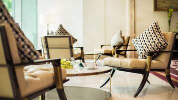 A modern lounge area with leather armchairs, a glass coffee table, and patterned throw pillows.