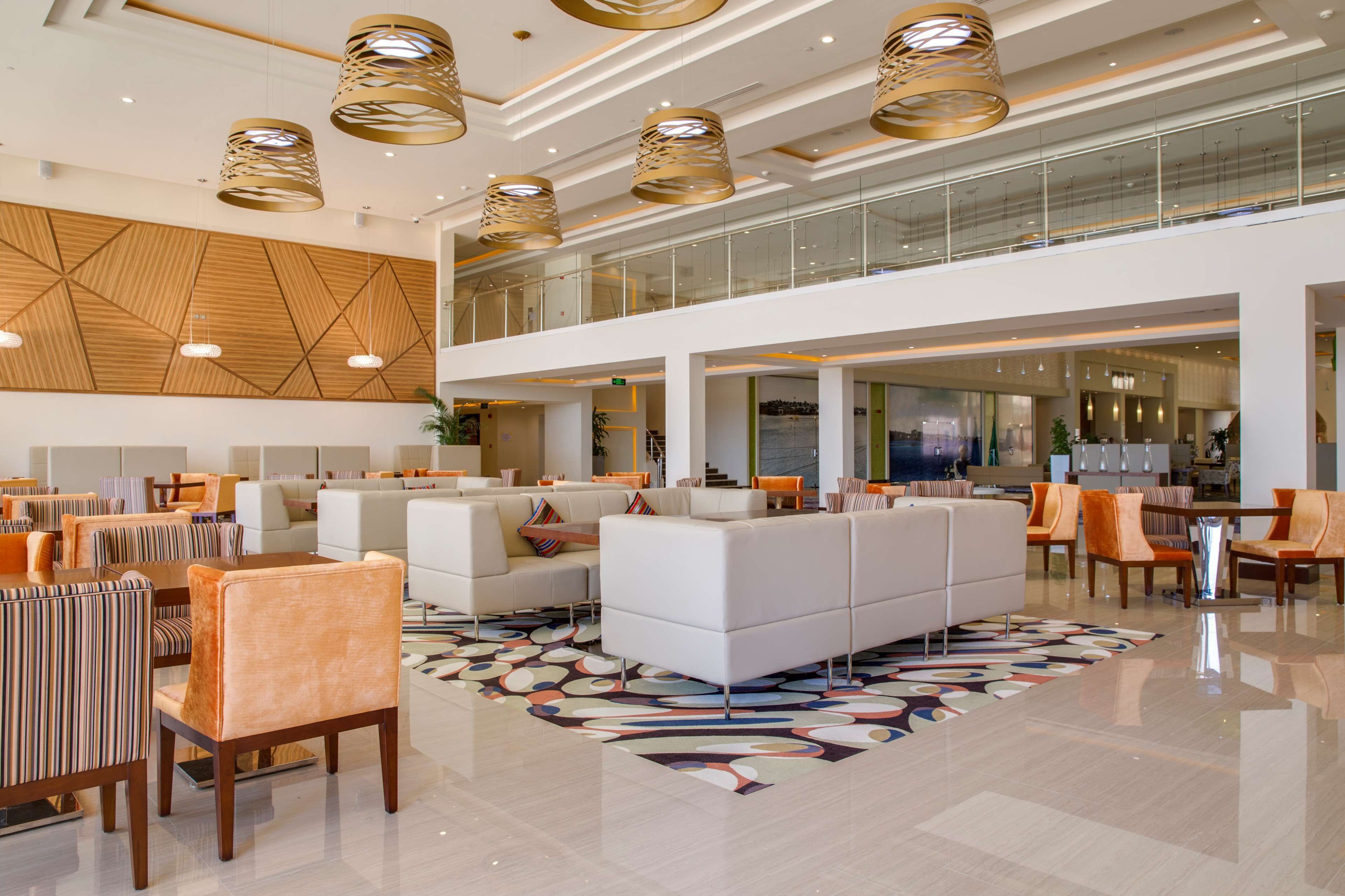 A spacious lobby with high ceilings, modern lighting fixtures, and a mix of seating areas including sofas and chairs.