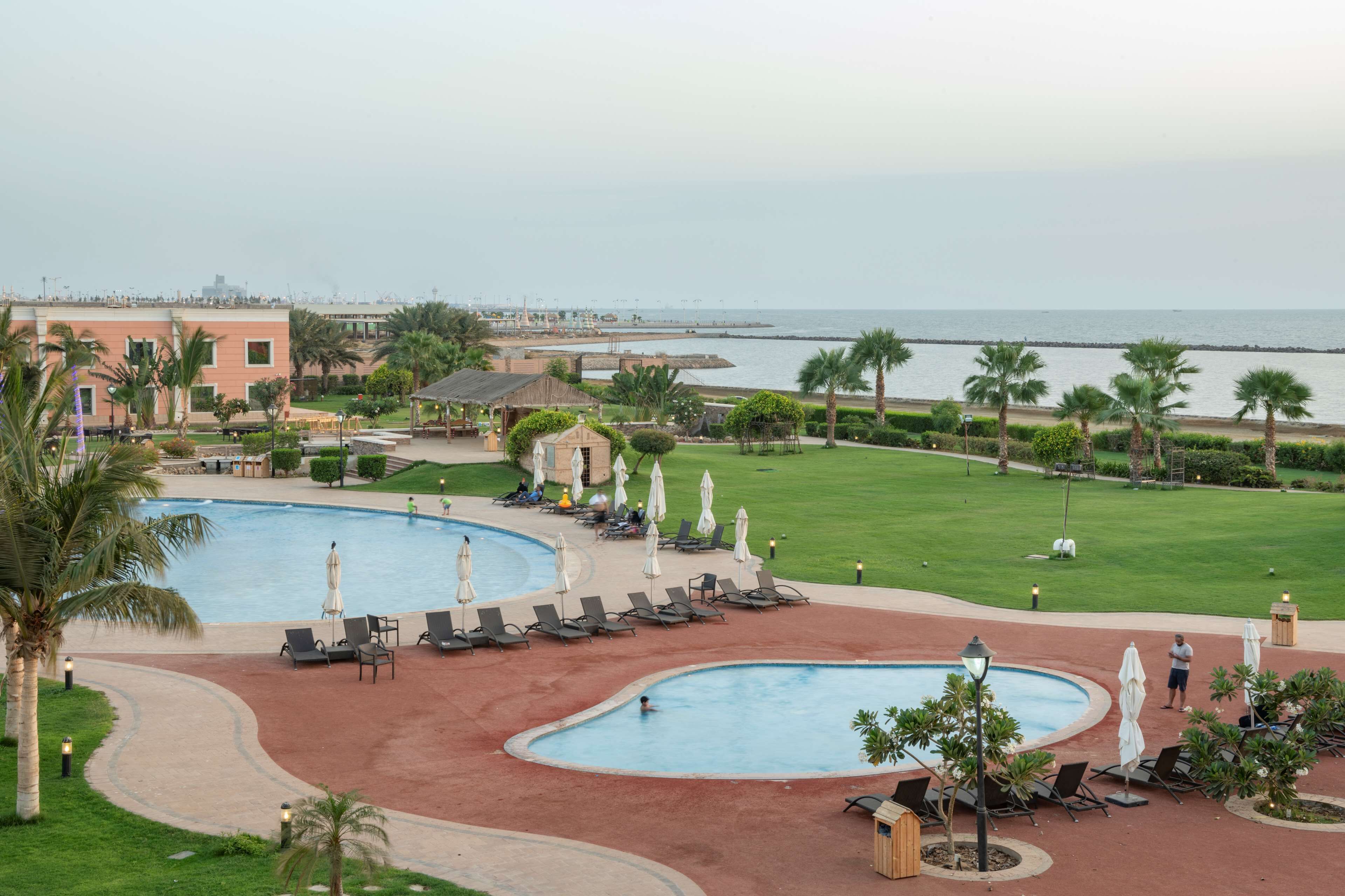 Un resort con varias piscinas, una playa y un césped bien cuidado.
