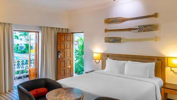 Une chambre d’hôtel avec un lit, une table ronde, une chaise, une porte en bois et une vue sur l’extérieur.