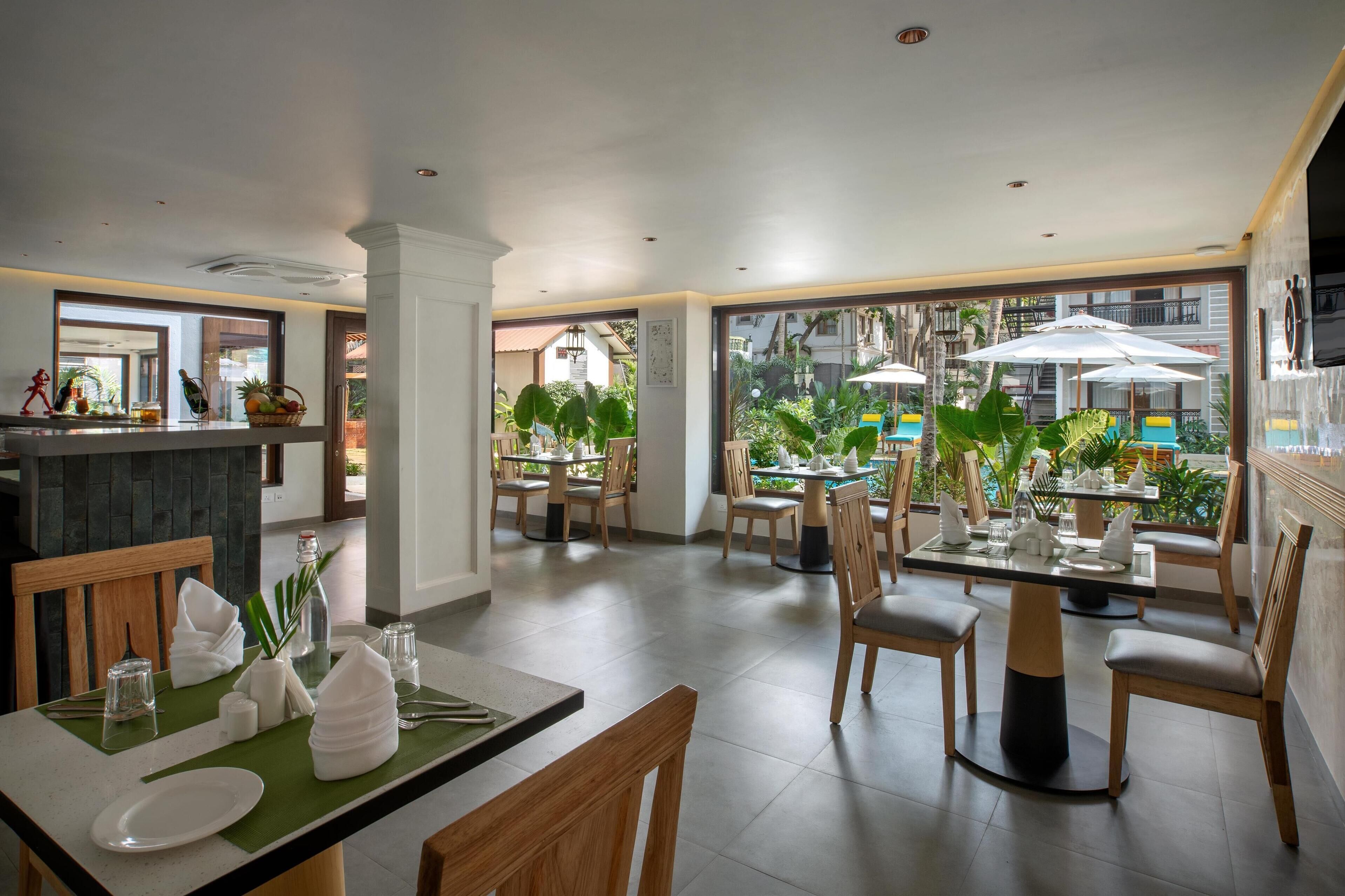 Un restaurant doté d’une salle à manger, d’un comptoir et de grandes fenêtres donnant sur un jardin.