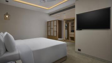 Una habitación de hotel moderna con una cama grande, un televisor de pantalla plana, un ventilador de techo y un vestidor.