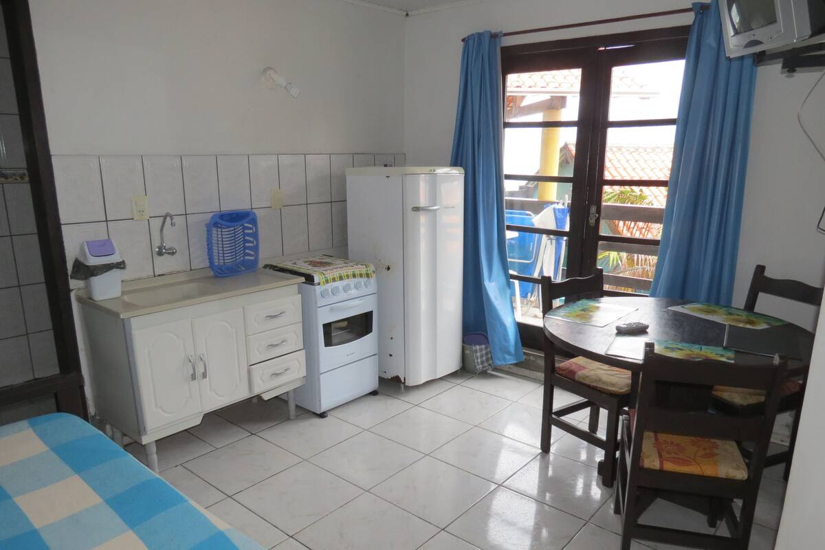 A compact kitchen with a stove, refrigerator, and a dining area with a table and chairs.