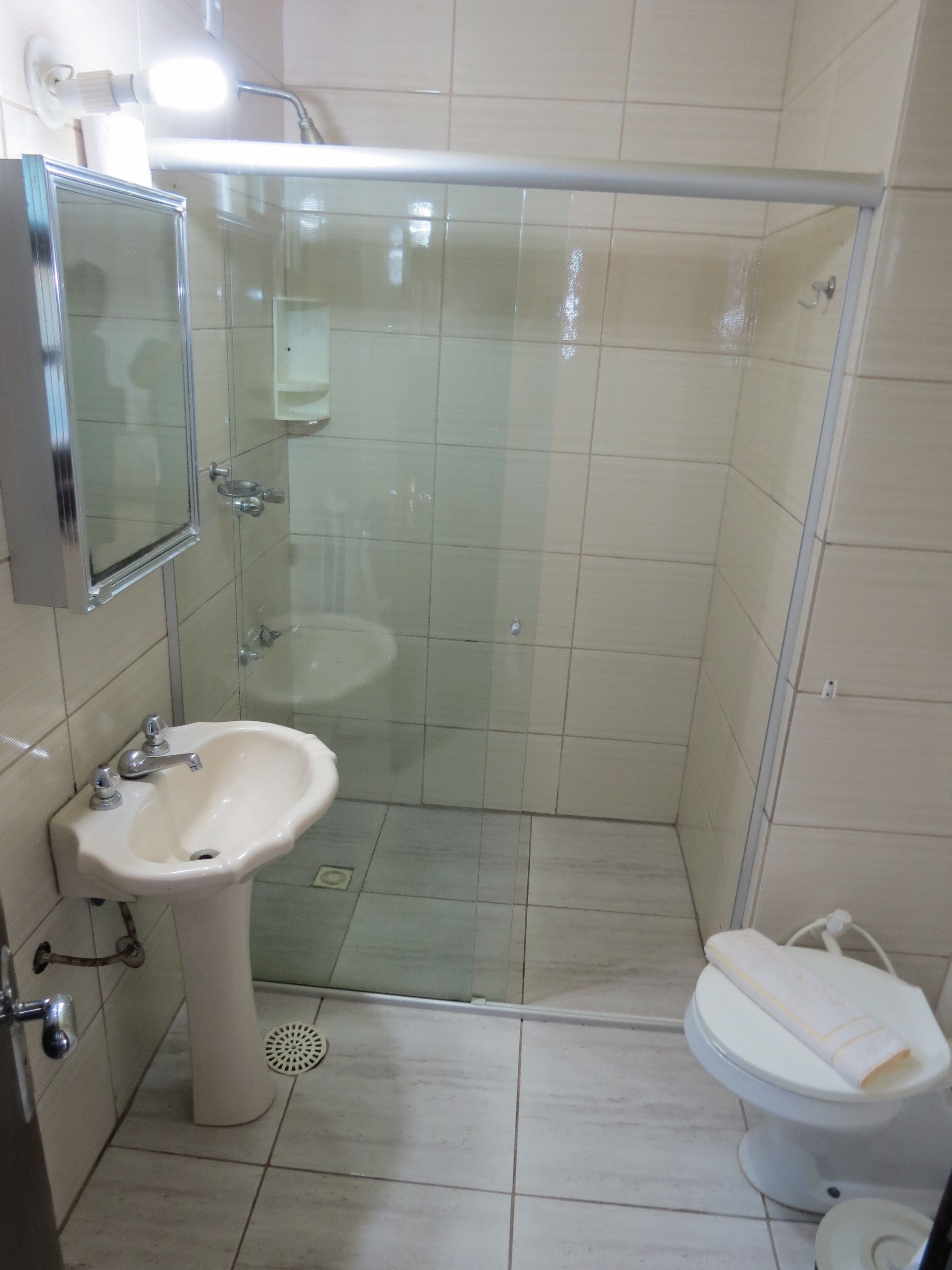 Un baño con ducha de vidrio, lavamanos, inodoro y espejo.