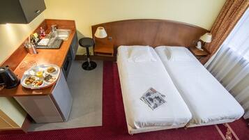 A hotel room with a bed, a desk with a sink, and a breakfast tray.
