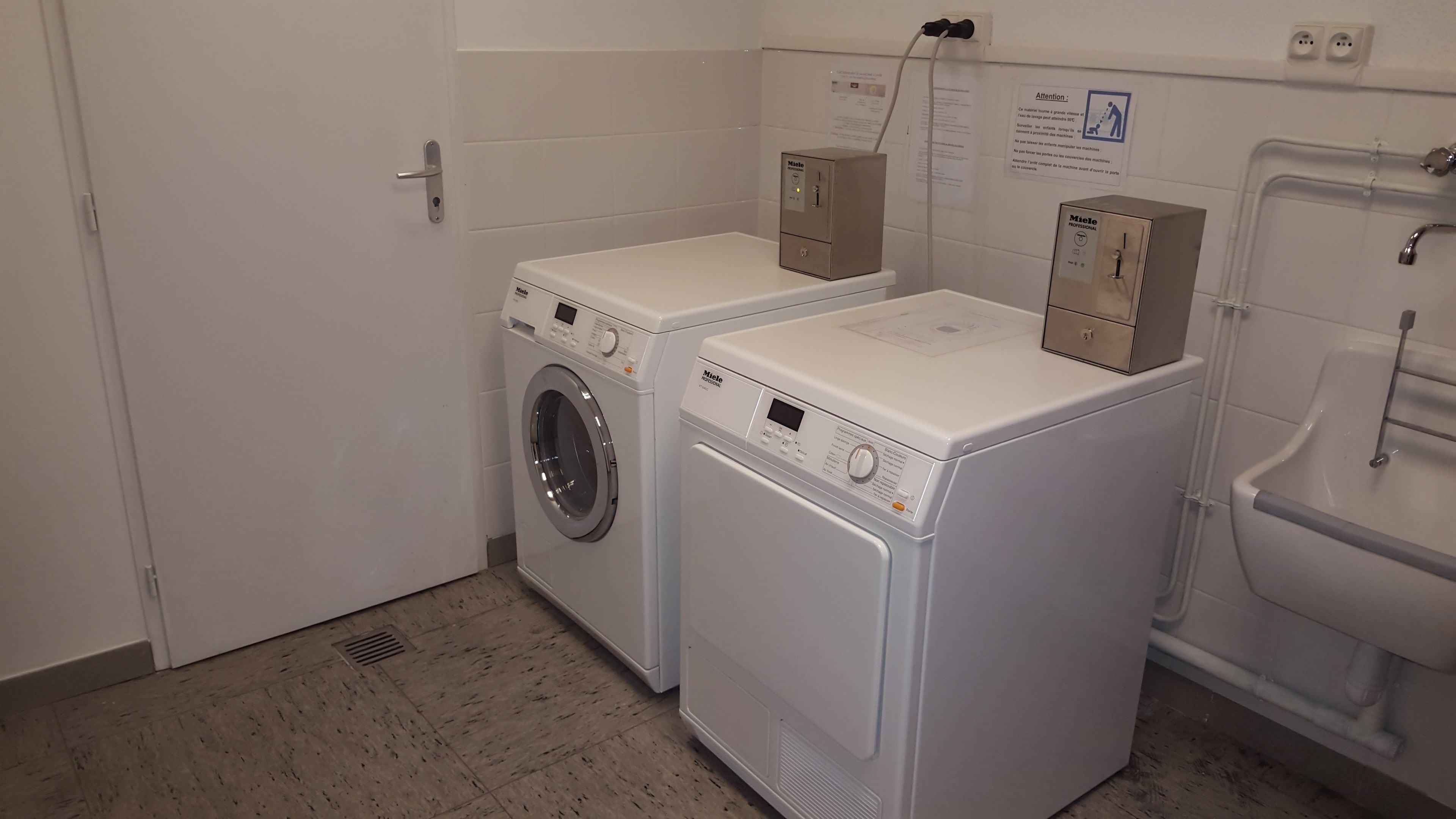 A laundry room with two front-loading washing machines and a dryer.