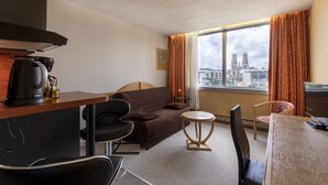 A hotel room with a bed, a desk, a chair, a small table, and a window with curtains. - KOSY Appart'Hôtels - Coeur de Ville  (Nancy)