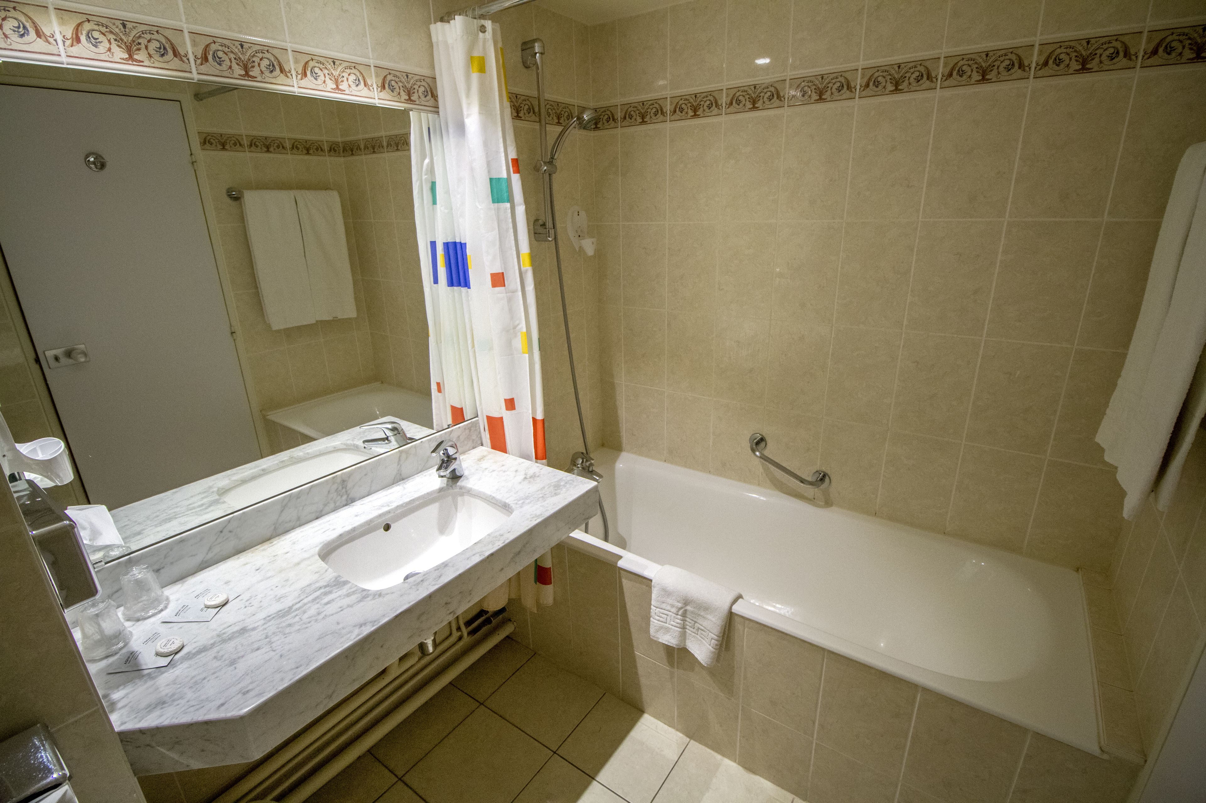 A bathroom with a large mirror, two sinks, a bathtub, and a shower.