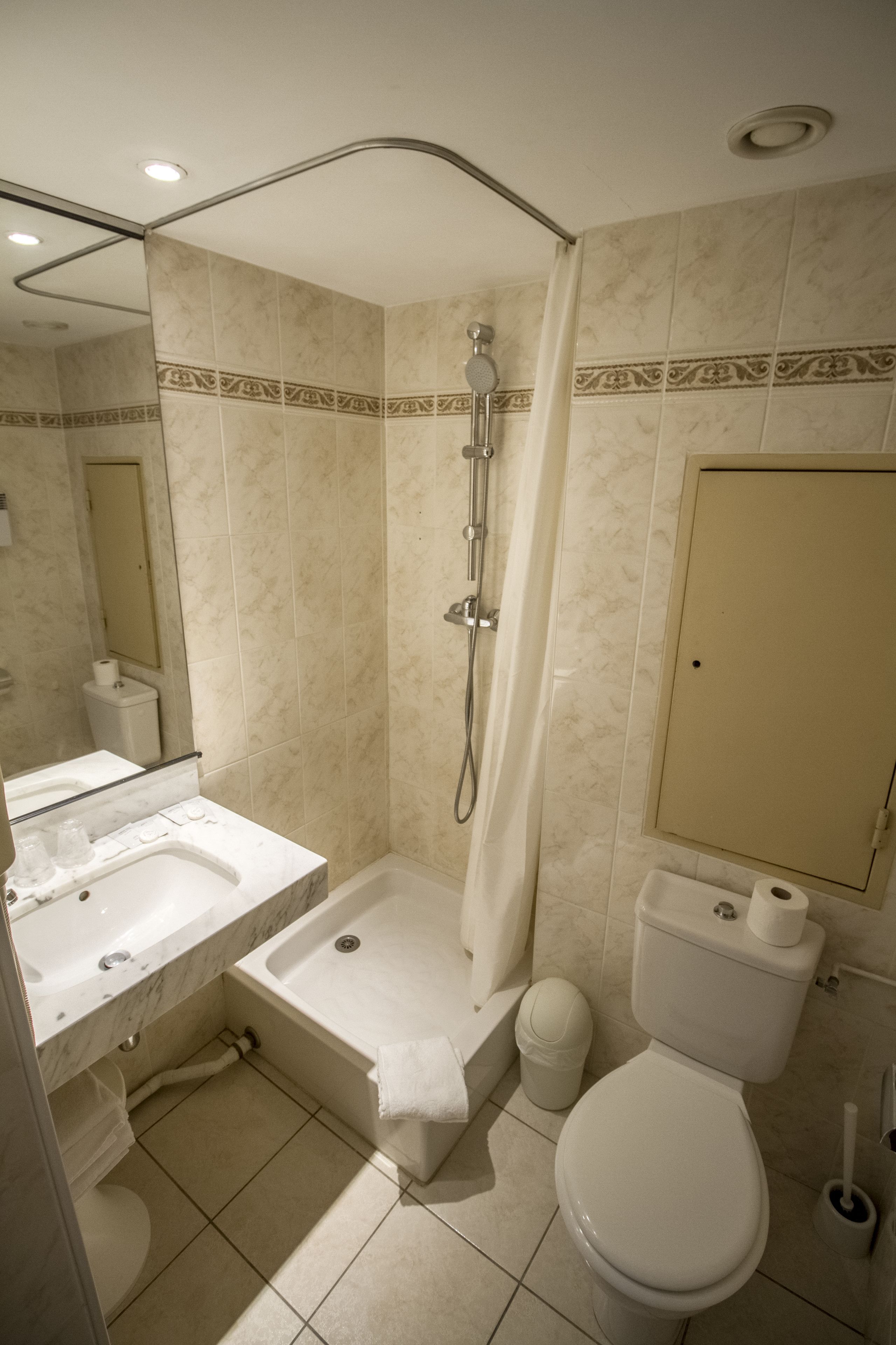 Une salle de bain avec douche, toilettes et lavabo.