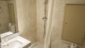 Une salle de bain avec douche, toilettes et lavabo.