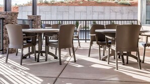 An outdoor patio with stone walls, wicker chairs, and tables, overlooking a desert landscape. - Sleep Inn & Suites Page at Lake Powell (Page)