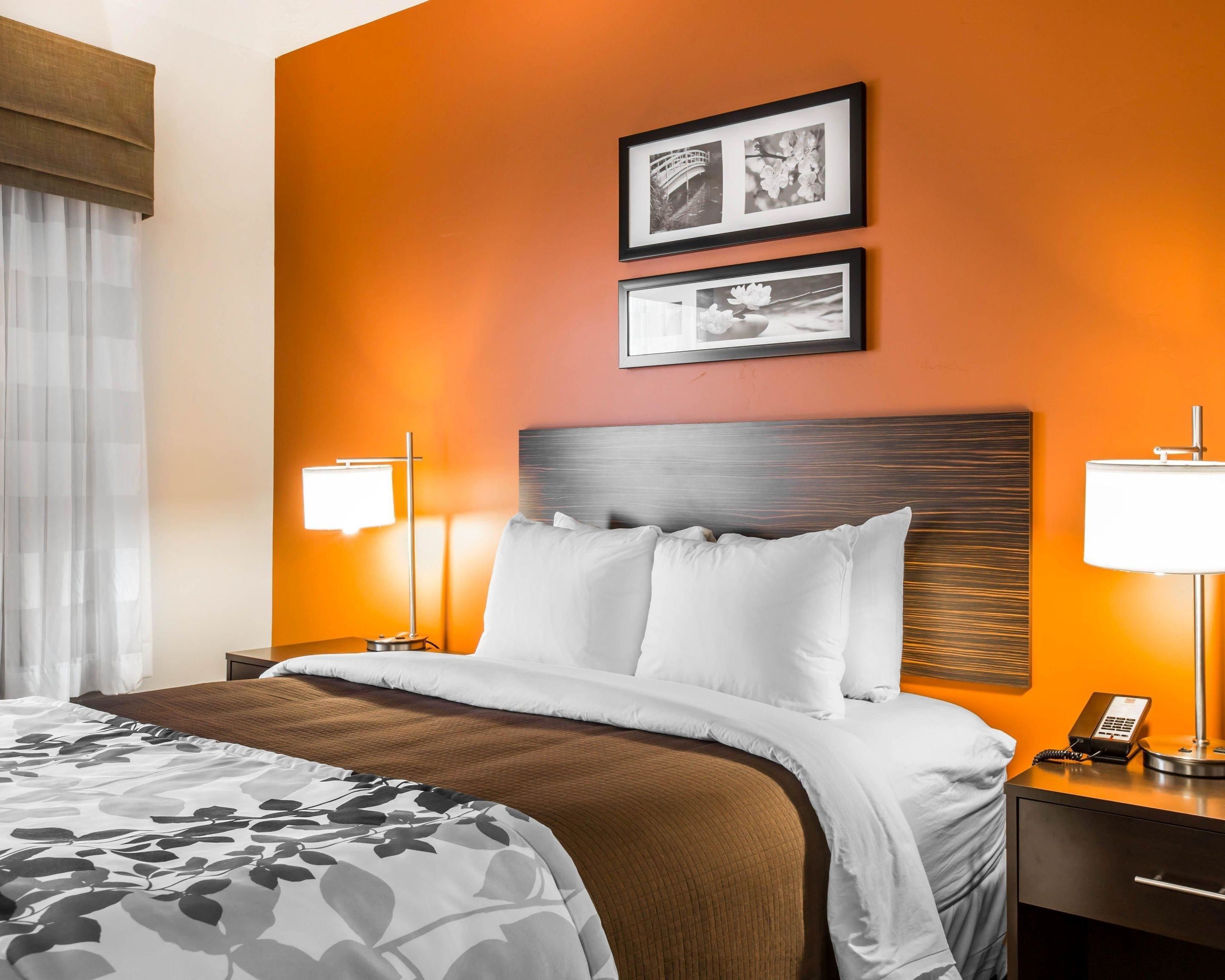 A hotel room with a bed, two bedside tables, a nightstand, and a wall-mounted telephone.