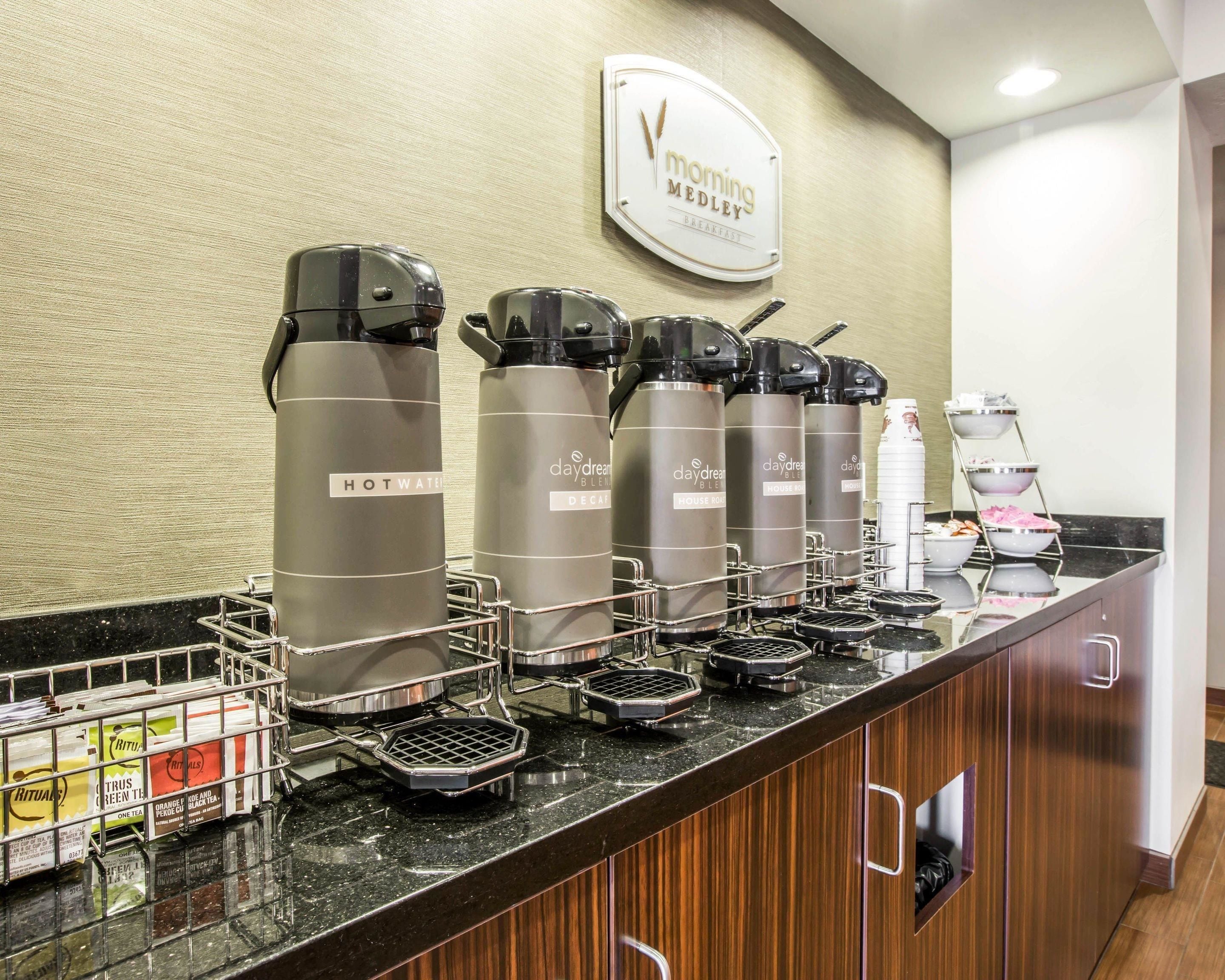 A breakfast bar with hot water dispensers, waffle makers, and a coffee machine.
