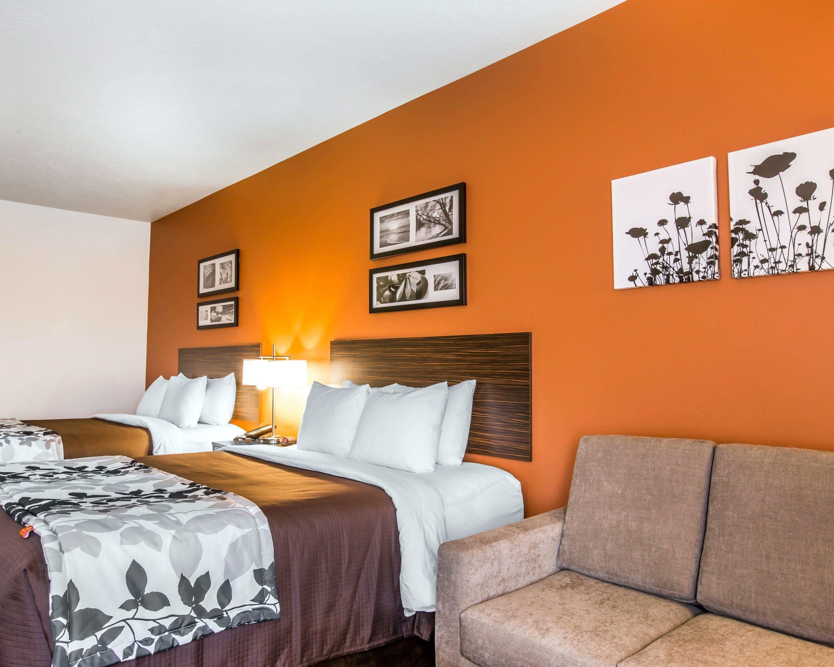 Een hotelkamer met twee bedden, een bank en kunstwerken aan de wanden.