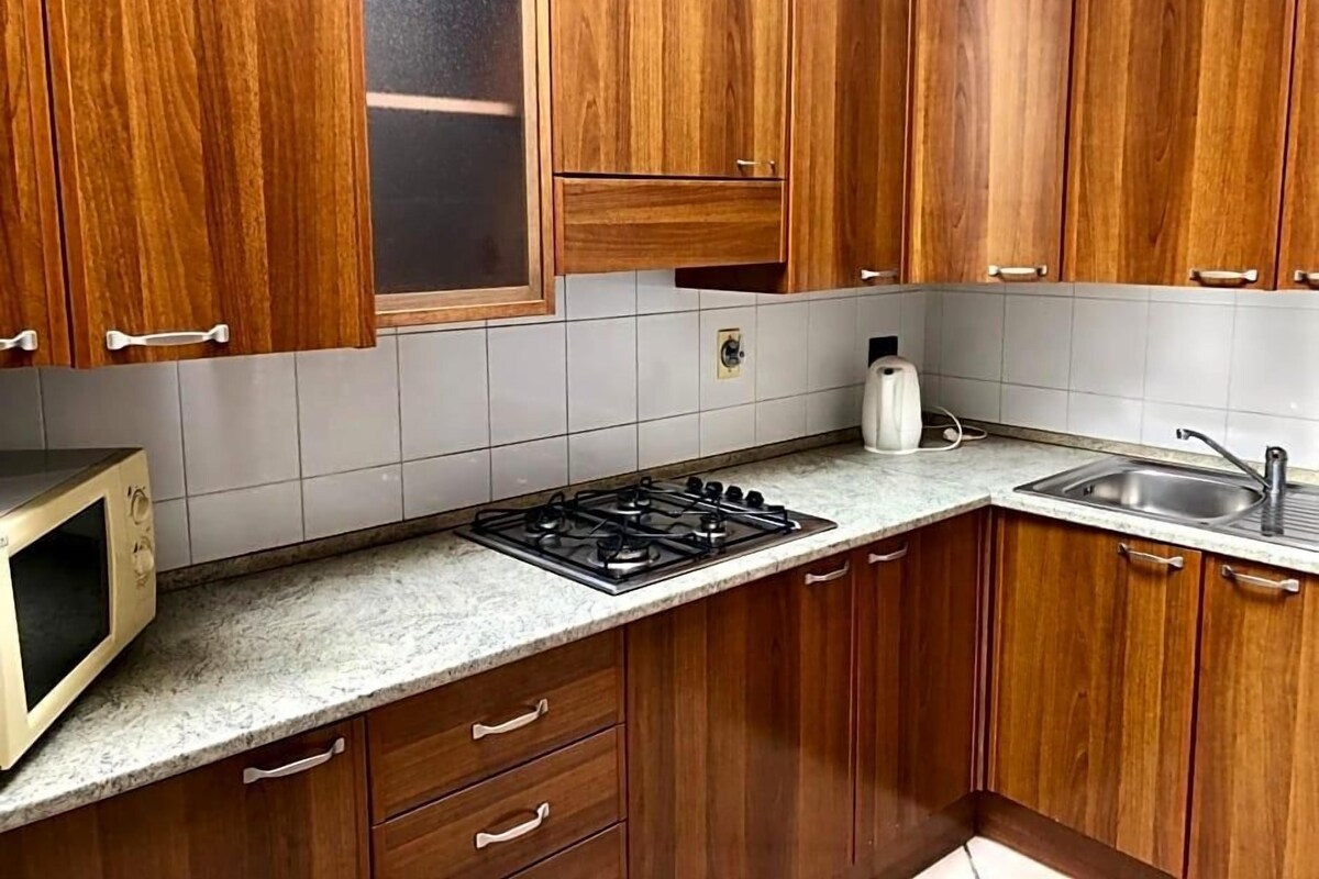 A kitchen with wooden cabinets, a gas stove, a microwave, and a sink.