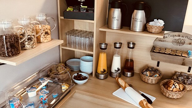 A breakfast bar with various food items, condiments, and a coffee maker. - KOSY Appart'Hôtels Troyes - City & Park (Troyes)